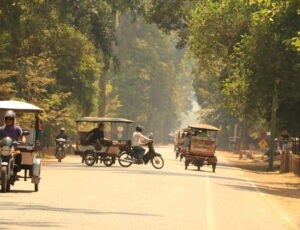 Tuk tuts driving down road in Cambodia Tuk tuts driving down road in Cambodia