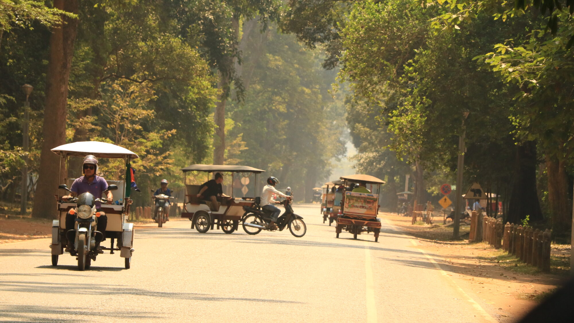 Tuk tuts driving down road in Cambodia Tuk tuts driving down road in Cambodia