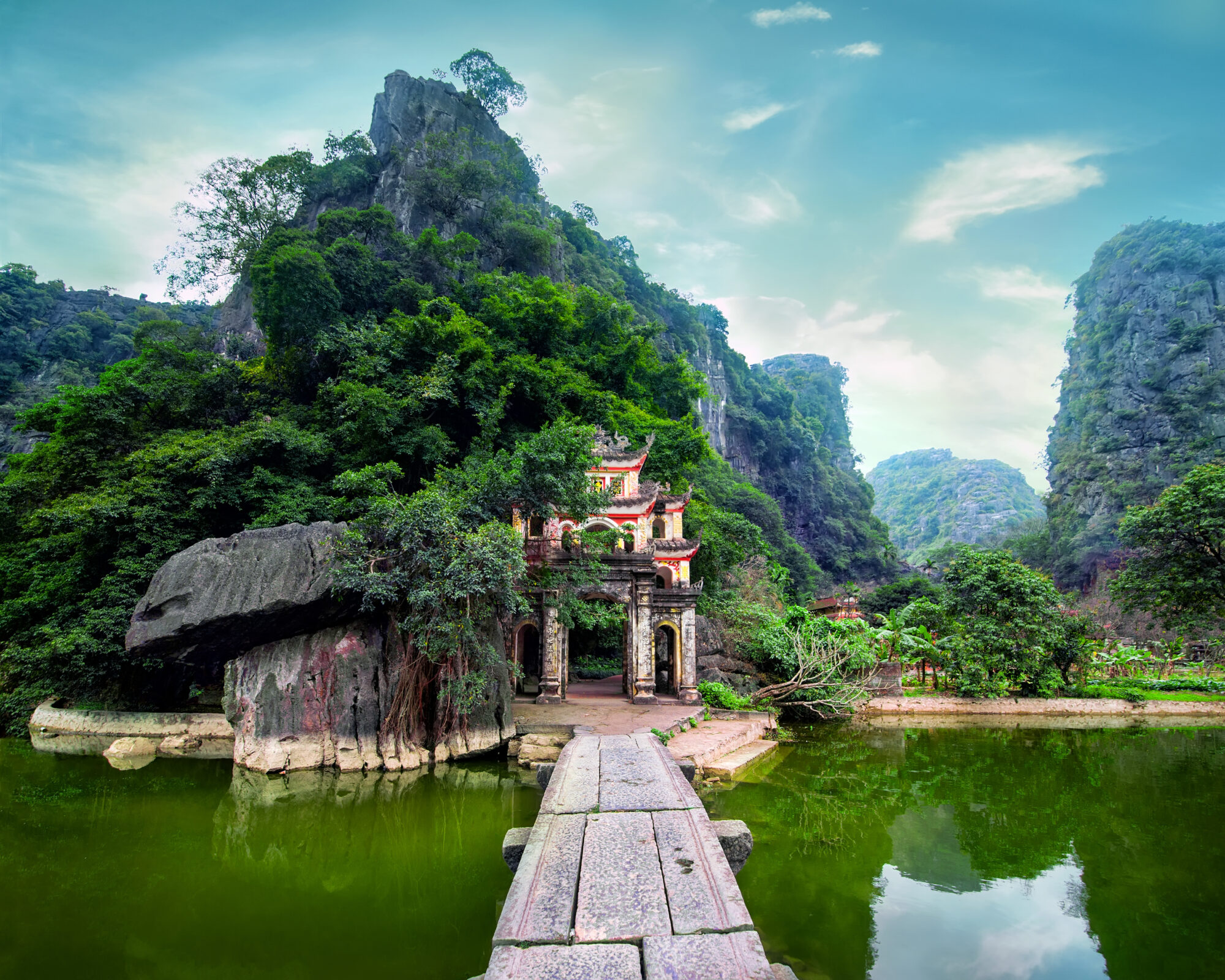 Outdoor park landscape with lake and stone bridge. Gate entrance to ancient Bich Dong pagoda complex dating to 1428. Ninh Binh, Vietnam travel destination