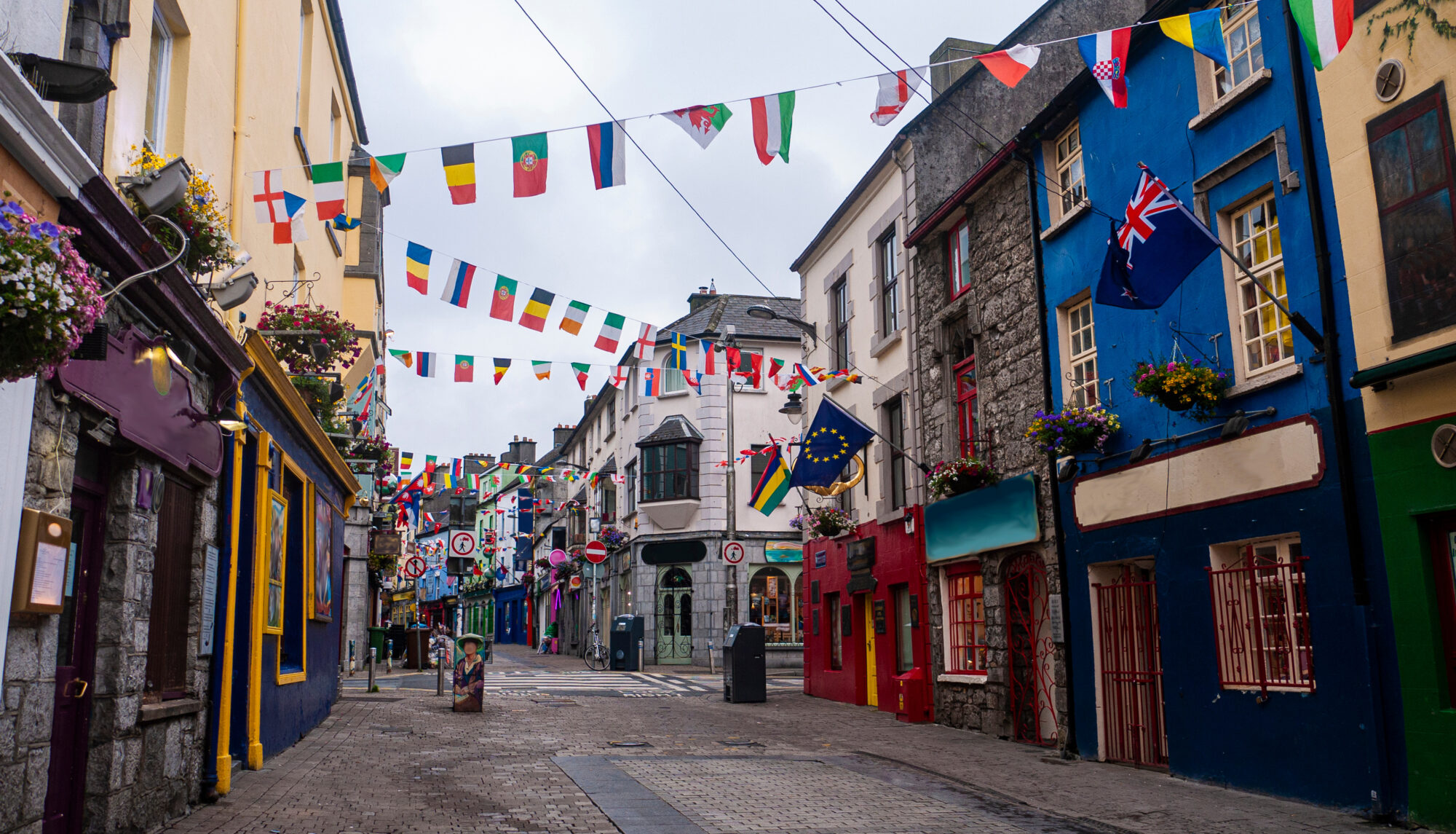 View of the main high street in Galway City with the brightly painted buildings and cobblestone streets on a cloudy day